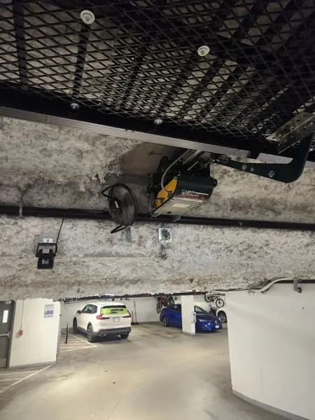 Ceiling-mounted parkade gate operator above a strata parking garage entrance