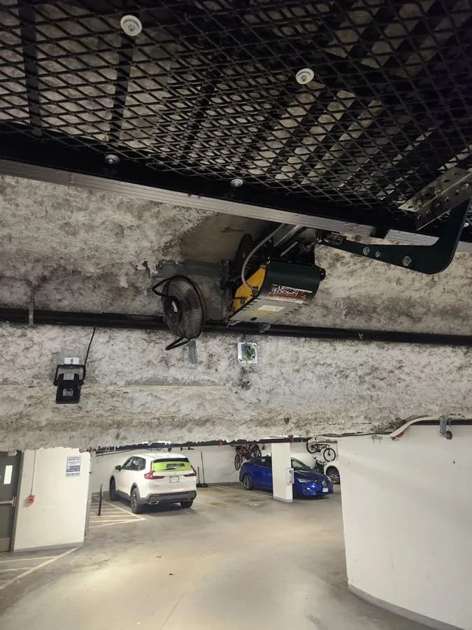 Ceiling-mounted parkade gate operator above a strata garage entrance